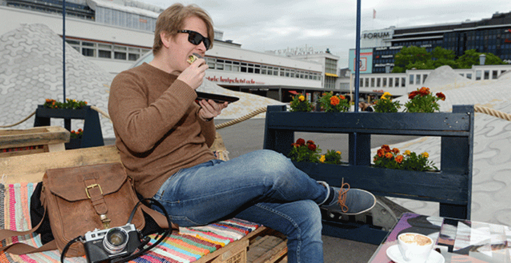 Mies söi aamupalaa ravintolan terassilla Helsingin Lasipalatsin aukiolla 1. kesäkuuta.