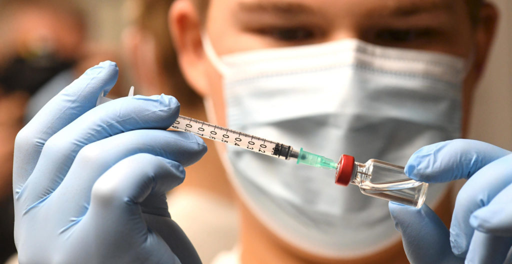 Kuvassa sairaanhoitaja laittaa rokotetta ruiskuun.