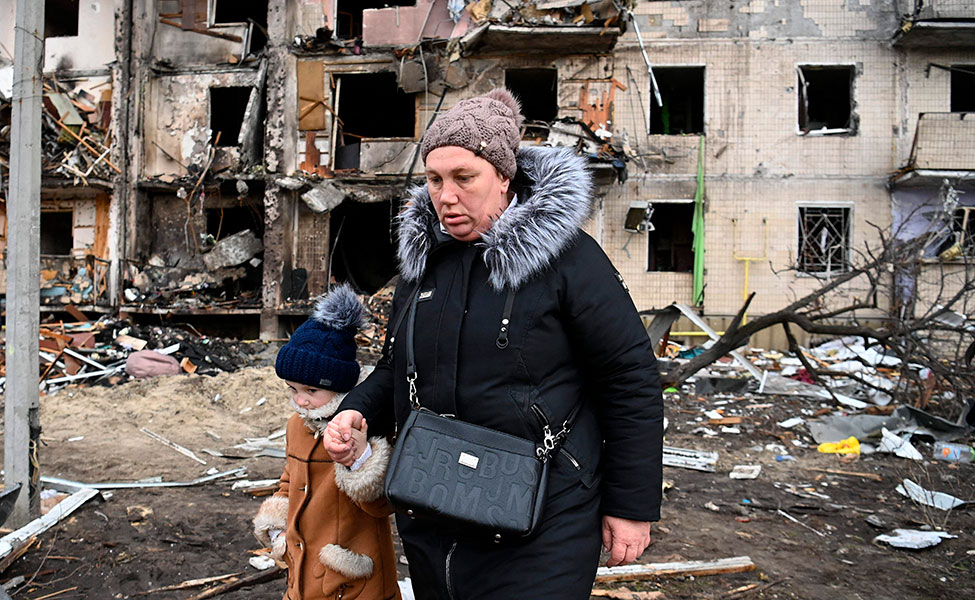 Nainen ja lapsi kulkevat tuhoutuneen talon ohi esikaupungissa Kiovassa.