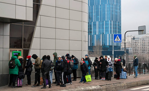 Pitkä jono ihmisiä, jotka odottavat pääsyä pankkiautomaatille ulkona Kiovassa.