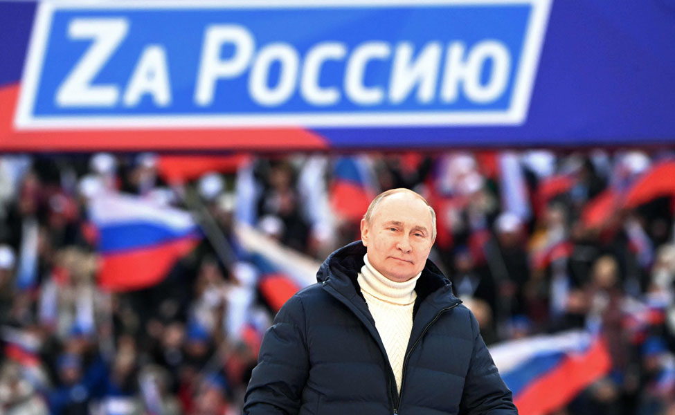 Kuvassa Venäjän presidentti Vladimir Putin on suuressa juhlassa. Siellä juhlittiin sitä, että Venäjä valtasi Krimin Ukrainalta kahdeksan vuotta sitten. Julisteessa Putinin takana lukee venäjäksi: ”Venäjän puolesta.”