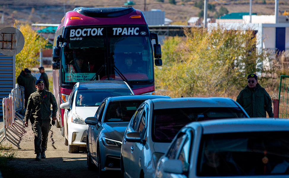 Mongolialaiset rajavartijat tarkistavat papereita autoilijoilta, jotka odottavat pääsyä Venäjältä Mongoliaan.