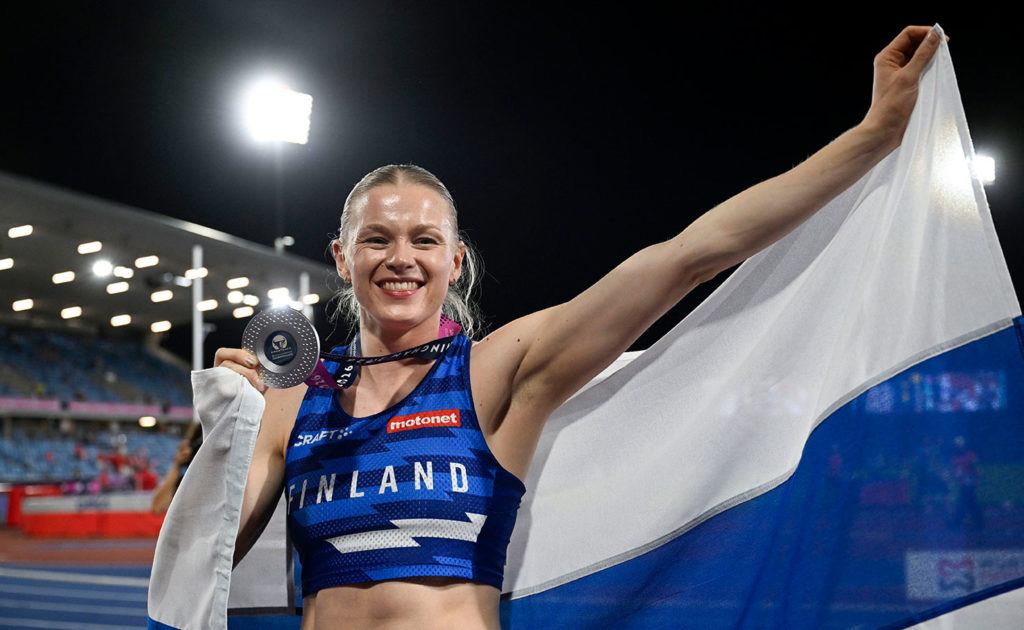 Wilma Heltelä heiluttaa Suomen lippua hopeamitali kaulassa stadionilla.
